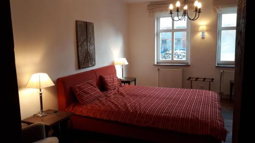 a bedroom with a red bed and two windows at Lindenhof in Wahrenberg