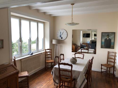 uma sala de jantar com uma mesa e um relógio na parede em Maison Bretagne em Matignon