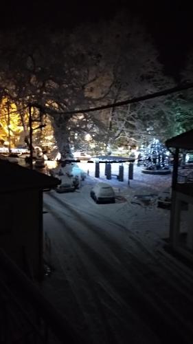 a snowy street at night with a car parked at Guest House Sakis. in Órma