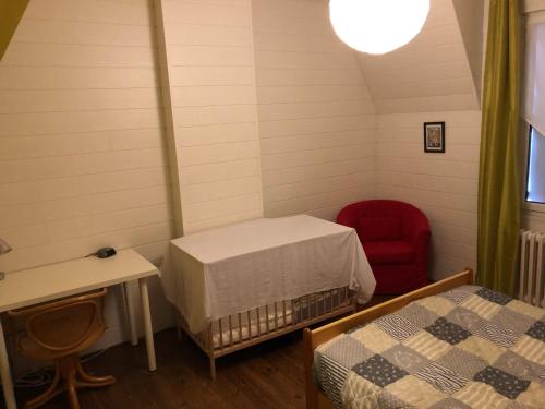 a room with two beds and a red chair at Maison Matignon Bretagne in Matignon