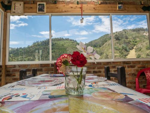 a vase of flowers sitting on a table in front of a window at HOSPEDAJE BELLA VISTA MONGUI in Monguí