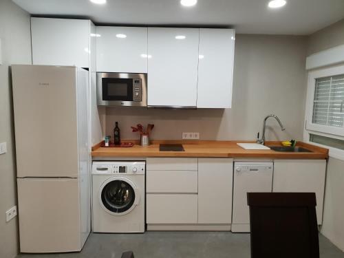 eine Küche mit weißen Schränken und einer Waschmaschine und einem Trockner in der Unterkunft Moderno y Luminoso Apartamento in Sevilla