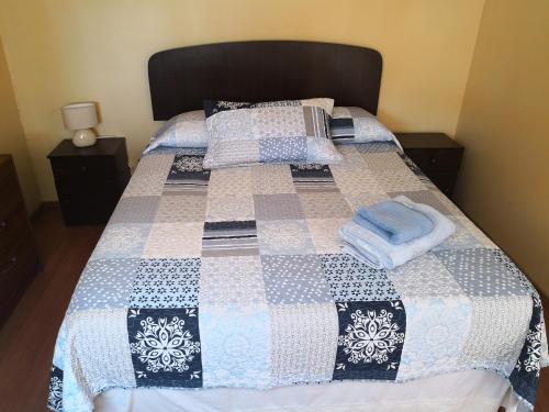 a bed with a blue and white quilt on it at Hostal Luna del Mar 840-B in La Serena
