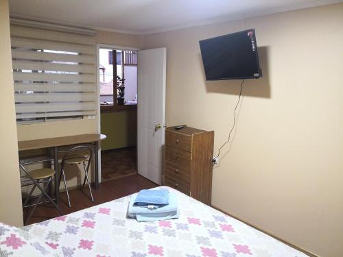 a bedroom with a bed with a desk and a television at Hostal Luna del Mar 840-B in La Serena