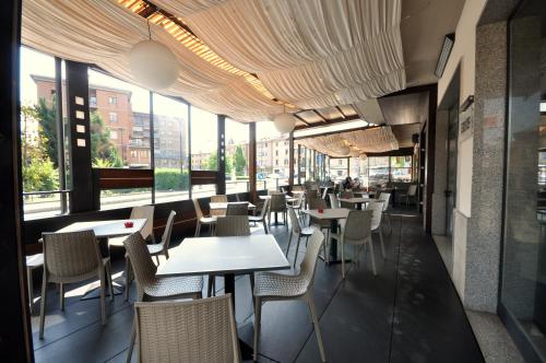 un restaurant avec des tables, des chaises et des fenêtres dans l'établissement Drake, à Maranello