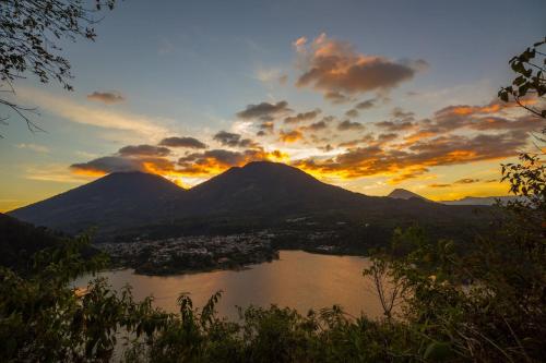 a view of a lake at sunset with mountains at Hotel Toliman in San Lucas Tolimán