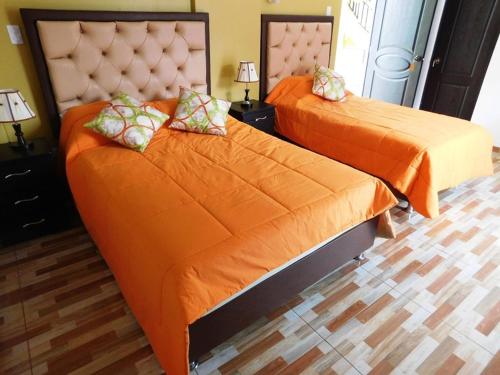 two beds with orange sheets in a bedroom at Reggio Green Hotel in Abancay