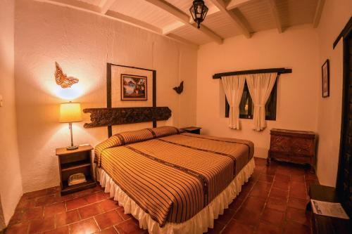 a bedroom with a bed and a lamp in it at Hotel Toliman in San Lucas Tolimán