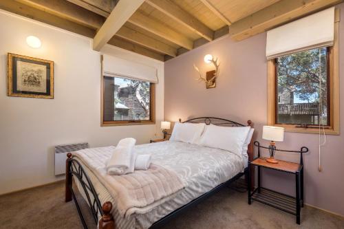 a bedroom with a bed and two windows at Burrinjuck in Dinner Plain