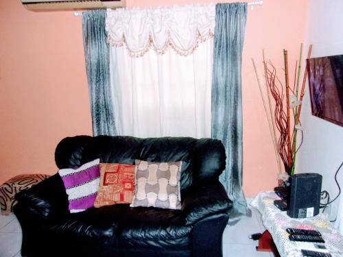 a black leather couch sitting in front of a window at Central Oaklands Kingston Apt in Kingston