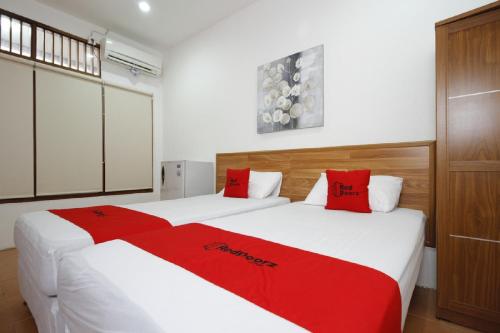 Duas camas num quarto com almofadas vermelhas em RedDoorz Plus near Plaza Indonesia em Jacarta