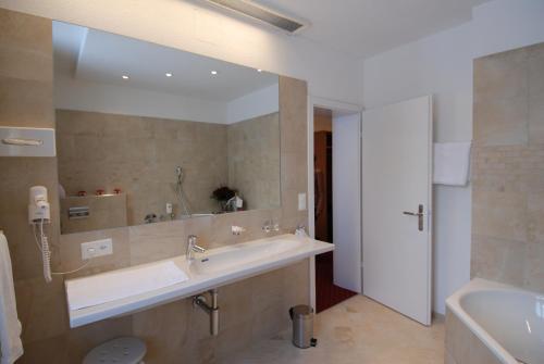 ein Badezimmer mit einem Waschbecken und einem großen Spiegel in der Unterkunft Hotel Schweizerhof in Engelberg