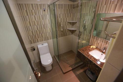 uma casa de banho com um chuveiro, um WC e um lavatório. em Pantai Regal Hotel em Kuantan