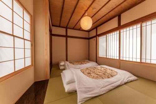 2 Betten in einem Zimmer mit 2 Fenstern in der Unterkunft cup of tea in Takayama