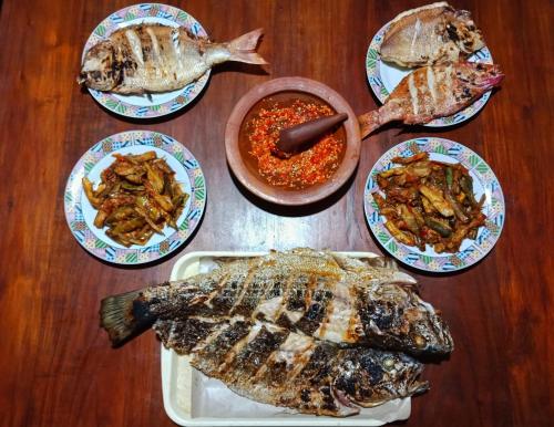 a table topped with plates of fish and sauce at Watukarung Prapto Homestay in Kalak