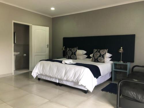 a bedroom with a large bed with a black headboard at Odelia Guest House in Mokopane