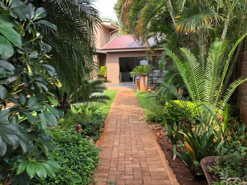 a brick path in front of a house with palm trees at Odelia Guest House in Mokopane