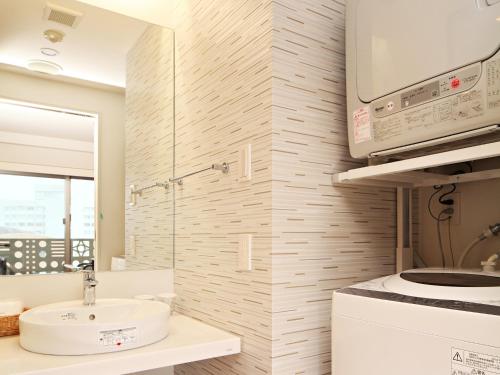 ein Badezimmer mit einem Waschbecken und einer Mikrowelle in der Unterkunft Smart Condo Tomari in Naha