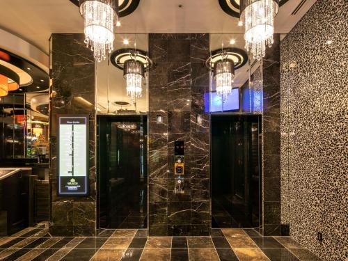 a lobby with black marble walls and chandeliers at APA Hotel Nihombashi Bakurocho Ekimae in Tokyo