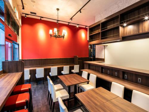 a restaurant with wooden tables and chairs and a red wall at APA Hotel Nihombashi Bakurocho Ekimae in Tokyo