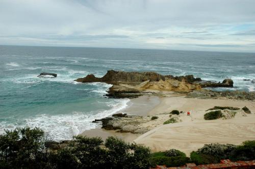 a beach with rocks in the water and the ocean at Dis Al in Oubosrand