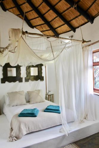 a bedroom with a white bed with a canopy at The Little Round House in Umtwalumi