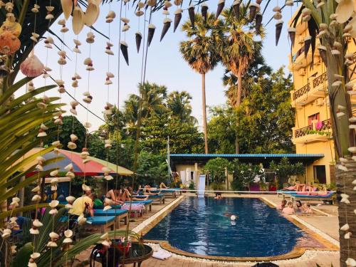 une piscine dans un hôtel avec des personnes assises autour de lui dans l'établissement Blue Diamond Hostel, à Battambang