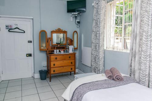 a bedroom with a bed and a mirror and a dresser at @karoo Guesthouse in Graaff-Reinet