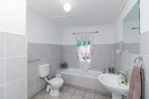 a bathroom with a toilet and a tub and a sink at @karoo Guesthouse in Graaff-Reinet