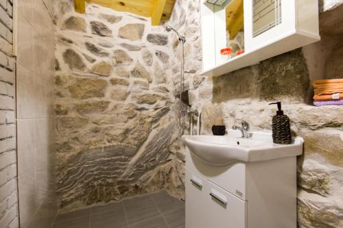 a bathroom with a sink and a stone wall at Ethno House Kosic in Herceg-Novi