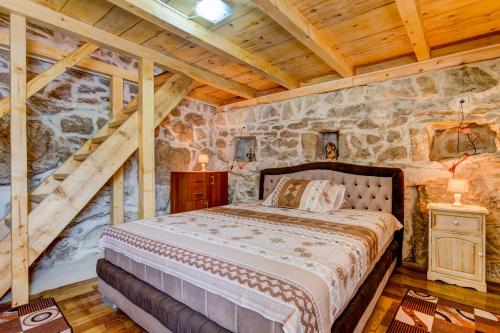 a bedroom with a bed and a stone wall at Ethno House Kosic in Herceg-Novi