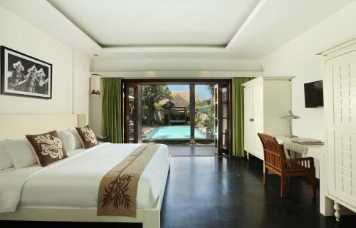 a bedroom with a bed and a desk and a pool at Nunia Boutique Villa in Seminyak