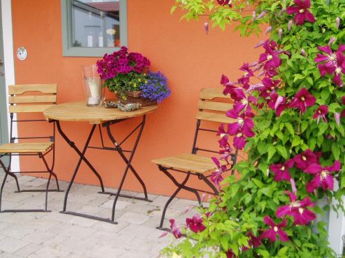 a table and chairs next to a wall with flowers at Weinhof am Nussbaum in Willanzheim