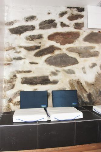 a desk with two chairs and a stone wall at Ferme Saint-Aubin in Sainte-Foy-Tarentaise
