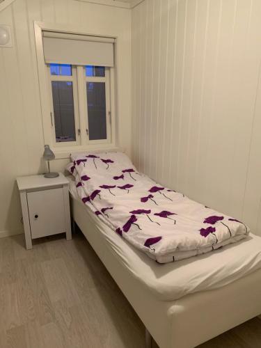 a bed in a white room with a window at Havbris in Bremnes