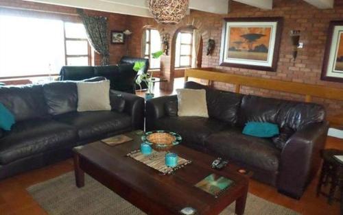 a living room with a leather couch and a coffee table at Isigidi Beach House in Port Shepstone