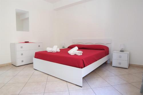 1 dormitorio con cama roja y blanca y muebles blancos en Cortile Fichi d'india, en Sciacca