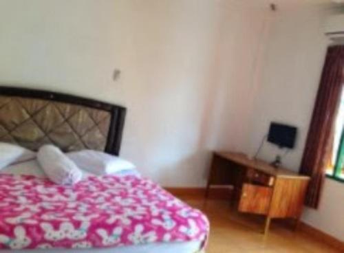 a bedroom with a bed with a red blanket and a table at Hotel Rembulan in Tebingtinggi