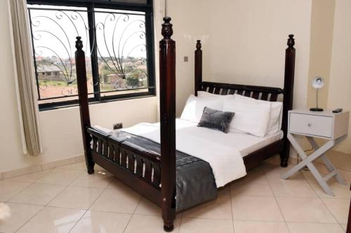 a bedroom with a canopy bed with a window at Trendy apartments in Entebbe