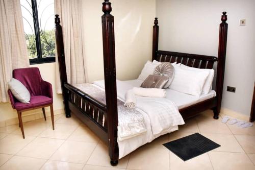 a bedroom with a canopy bed and a chair at Trendy apartments in Entebbe