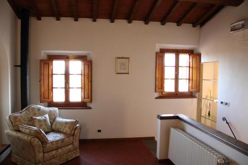 a living room with a chair and two windows at Podere Fichereto Tuscany Apartment in Florence countryside in Scandicci