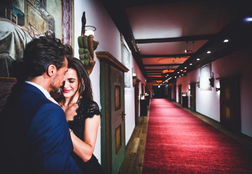 a man and a woman standing in a hallway with a red carpet at Hotel Klosterbräu in Seefeld in Tirol