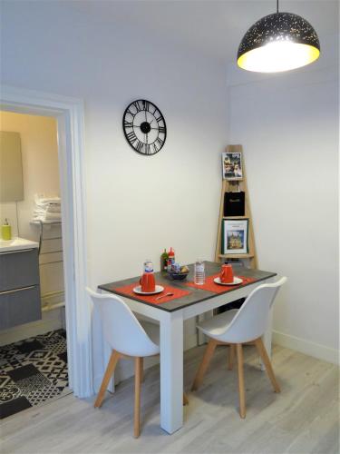 une table à manger avec deux chaises et une horloge murale dans l'établissement Les Clochers d'Or, à Chartres