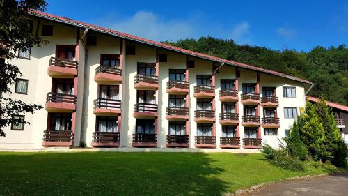 a large apartment building with balconies and a yard at Hotel Mladost in Tjentište