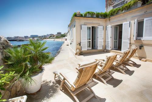 a group of chairs on a patio next to the water at Musciara Siracusa Resort in Syracuse