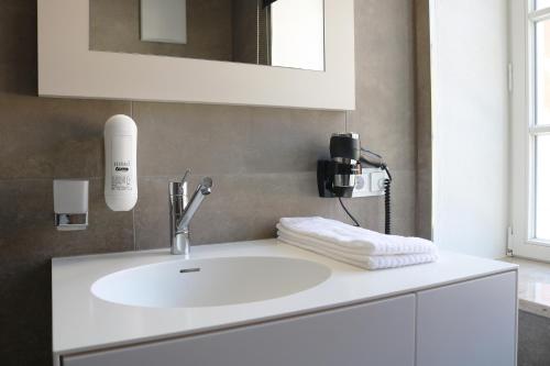 ein Badezimmer mit einem weißen Waschbecken und einem Spiegel in der Unterkunft GI Hotel by WMM Hotels in Giengen an der Brenz
