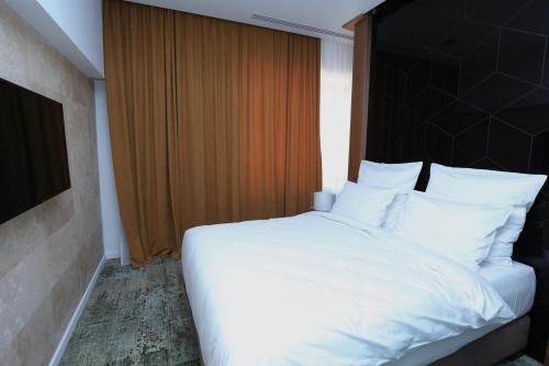 a bedroom with a large white bed with a window at Valentino Rooms in Focşani