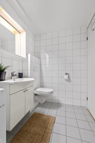a white bathroom with a toilet and a sink at BJØRVIKA APARTMENTS, Solsiden Area, Trondheim city center in Trondheim