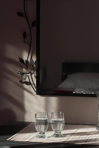 two glasses sitting on a table with a mirror at Selection Rooms in Belgrade