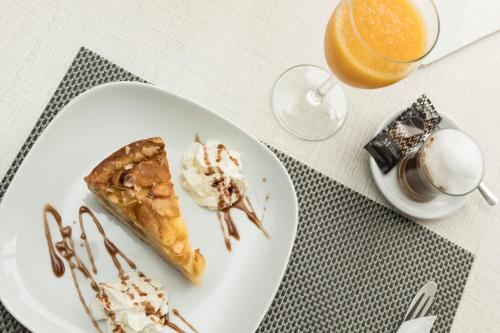 a white plate with a piece of pie and a glass of orange juice at Hotel d'Or in Cala d´Or